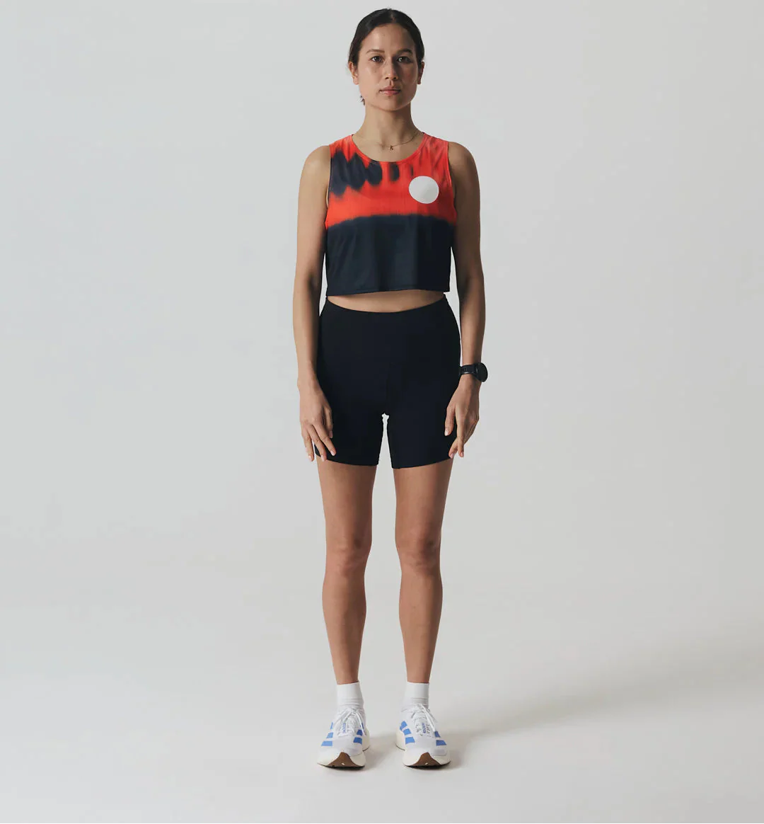 Male runner wearing an orange technical T-shirt and light grey shorts jogging along a waterfront path.