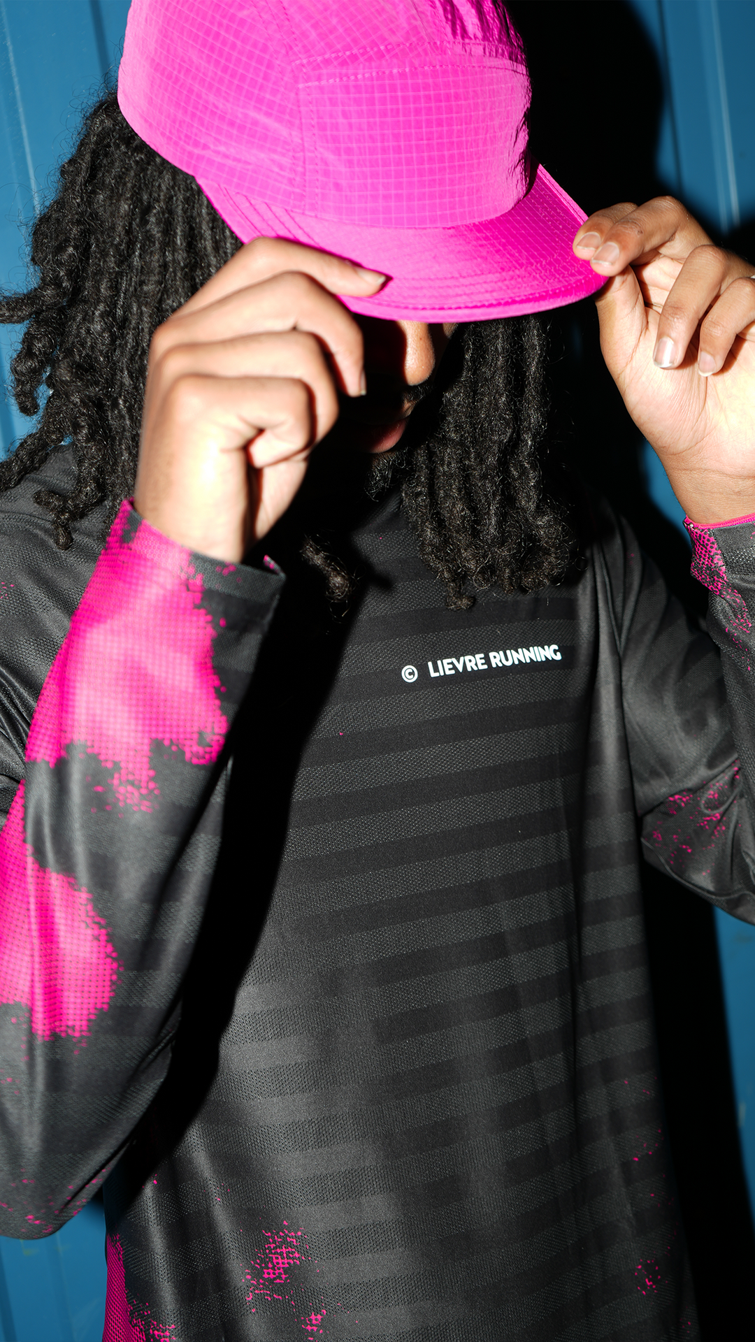 Side profile of a female runner wearing a white cap, pink sports sunglasses, and a zip-up performance top.
