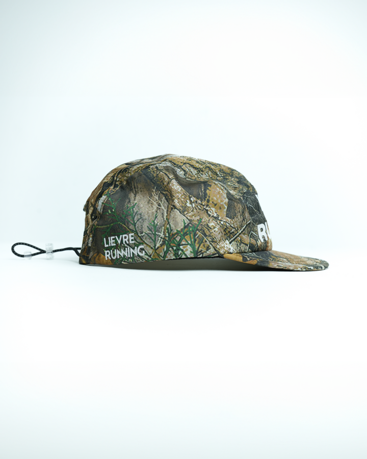 Lievre Running Wild Runner cap with camouflage print and bold “WILD-RUNNER” white text on front, five-panel silhouette with flat brim.