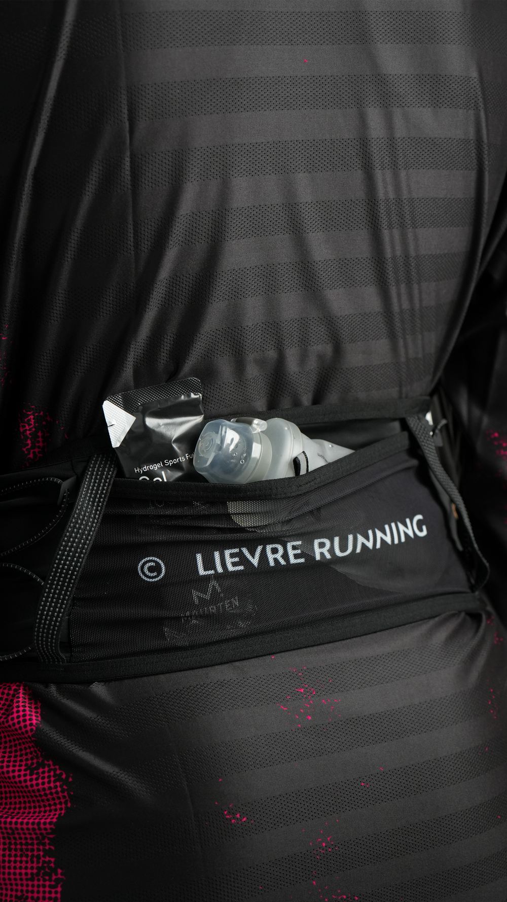 Lievre Running black ultra running belt, stretch technical fabric with multiple compartments, bungee cord system and white Lievre Running logo on front and back.