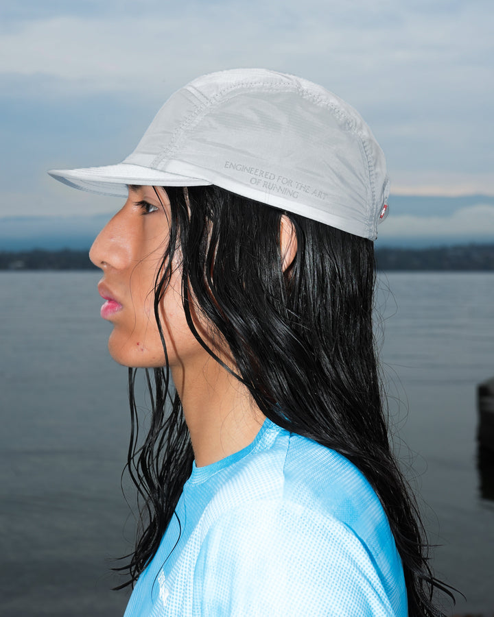 Lievre Running Art of Running Light Grey Cap, lightweight breathable technical fabric with adjustable strap, versatile neutral grey colorway for all-season running.
