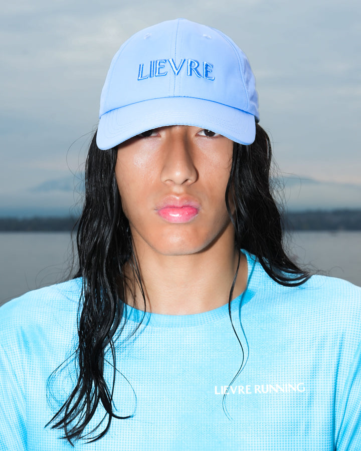 Lievre Running Signature Haze Blue Cap, ultra-lightweight nylon construction with DWR waterproof finish and minimal design, adjustable back strap.