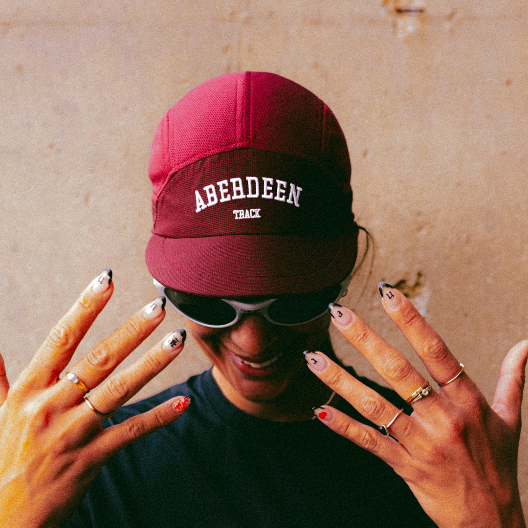 Participation Aberdeen running cap, maroon 5-panel with curved brim and white “ABERDEEN TRACK” embroidery.