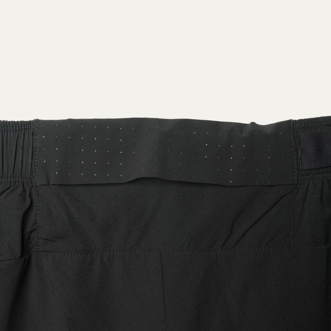 Plain black running shorts from Participation, minimalist design with balanced storage and integrated liner, photographed in a neutral studio setting.