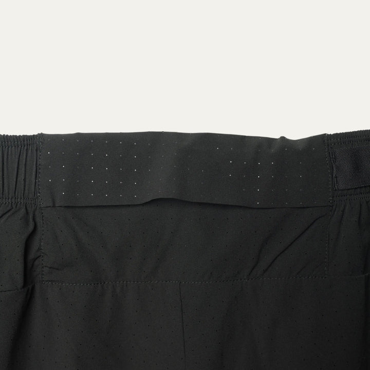Plain black running shorts from Participation, minimalist design with balanced storage and integrated liner, photographed in a neutral studio setting.