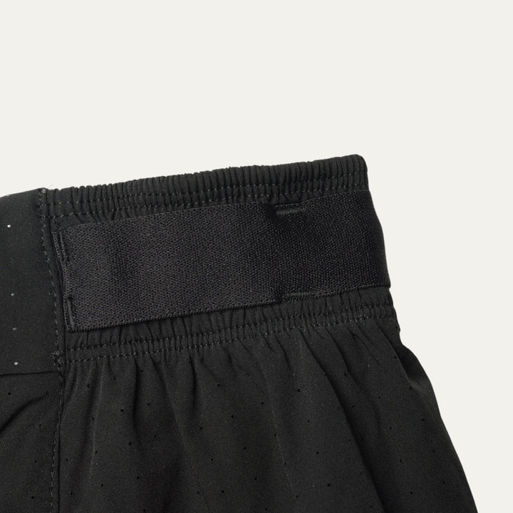 Plain black running shorts from Participation, minimalist design with balanced storage and integrated liner, photographed in a neutral studio setting.