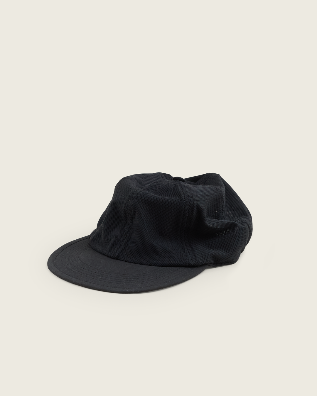 6-panel mesh running cap in Neutral and Black from Sysum, lightweight construction with soft foam bill and adjustable back strap visible, photographed in a neutral studio setting.