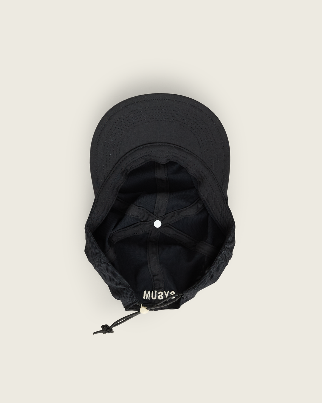 6-panel mesh running cap in Neutral and Black from Sysum, lightweight construction with soft foam bill and adjustable back strap visible, photographed in a neutral studio setting.