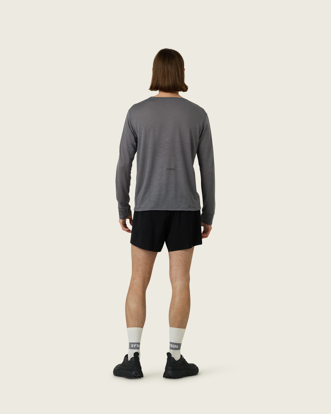 Men’s merino long-sleeve running top in Slate from Sysum, lightweight knit visible, photographed in a neutral studio setting.