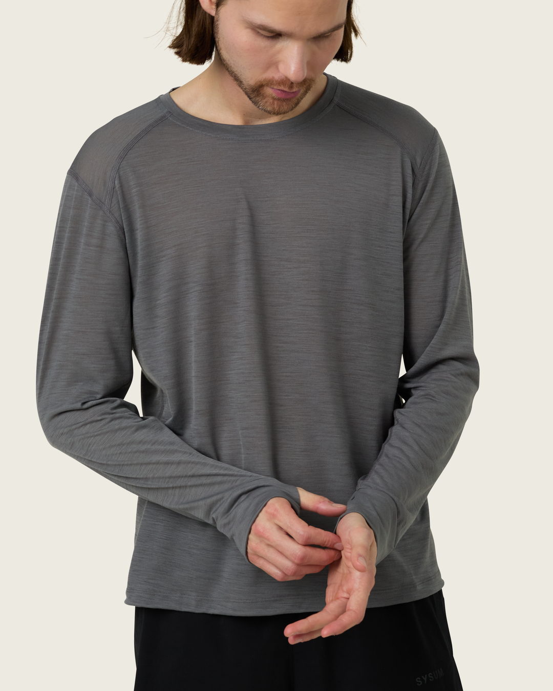 Men’s merino long-sleeve running top in Slate from Sysum, lightweight knit visible, photographed in a neutral studio setting.