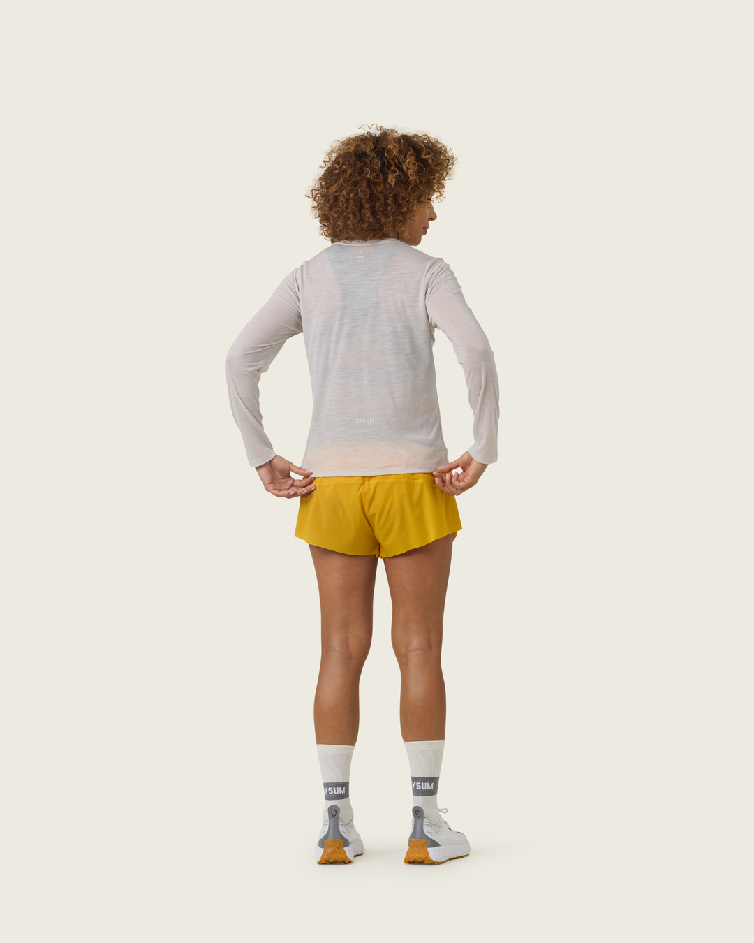 Women’s ultra-light merino long-sleeve running top in Pebble from Sysum, fine knit texture visible, photographed in a neutral studio setting.