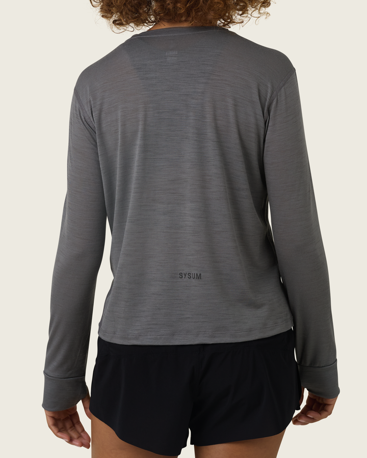Women’s merino long-sleeve running top in Slate from Sysum, lightweight knit texture visible, photographed in a neutral studio setting.