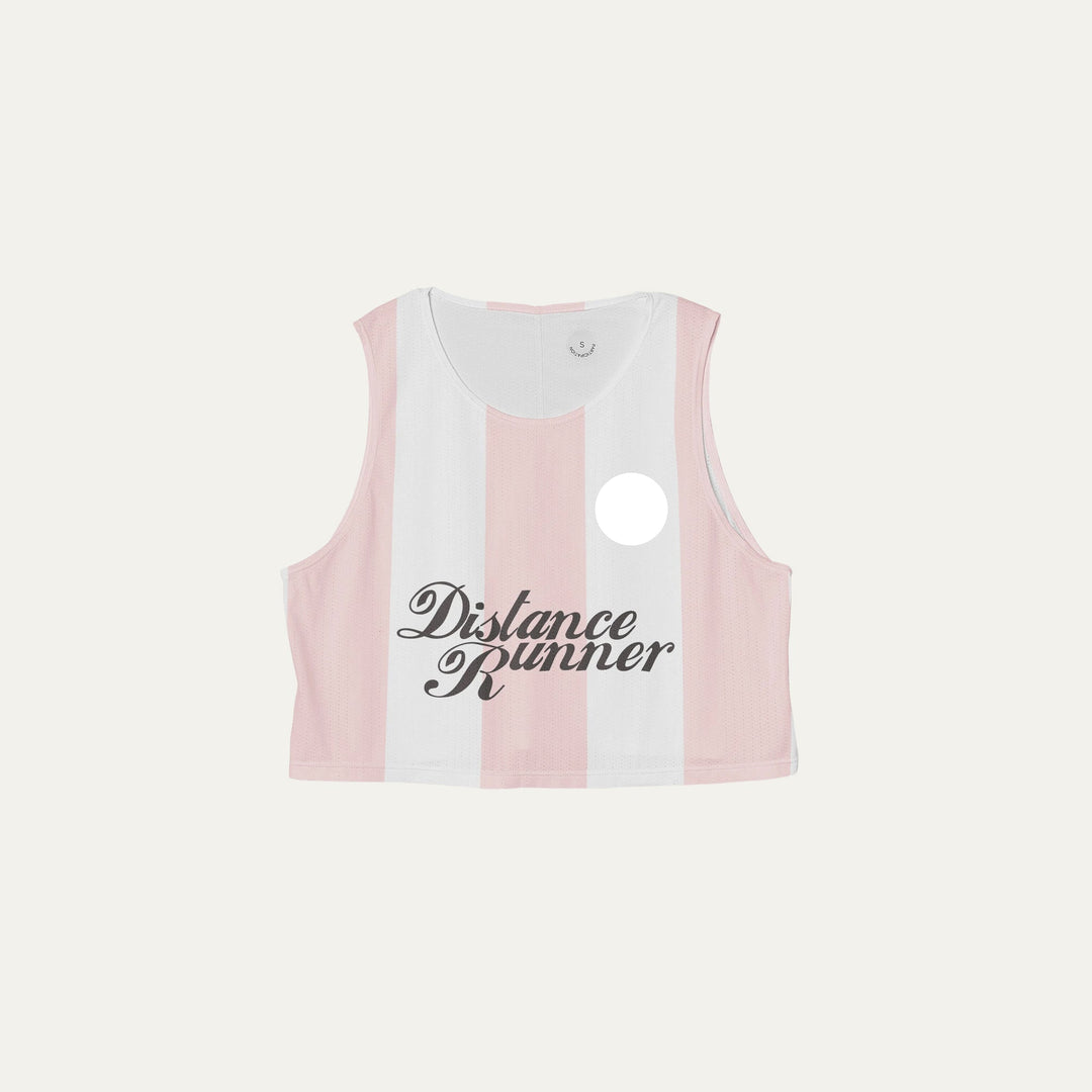 Cropped running singlet from Participation with pink stripe detailing, lightweight polyester construction for warm-weather training and racing, photographed in a neutral studio setting.