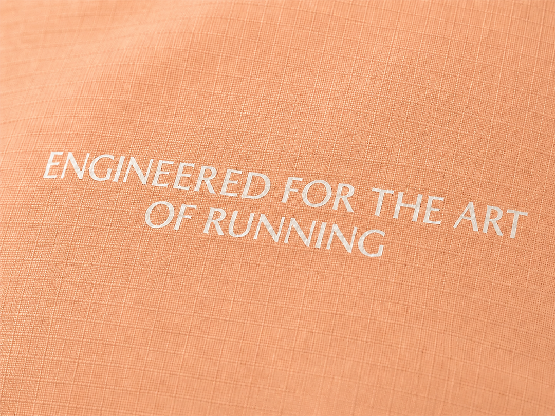 Lievre Running light salmon performance running cap, lightweight technical fabric with adjustable back cord and "Engineered for the Art of Running" text on the side panel.