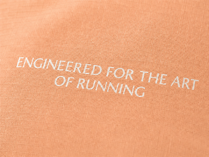 Lievre Running light salmon performance running cap, lightweight technical fabric with adjustable back cord and "Engineered for the Art of Running" text on the side panel.