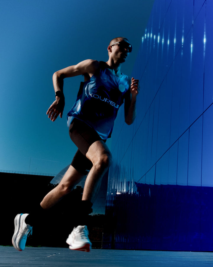 Limited Edition Participation Koureur Running Singlet in blue with white accents displayed on a hanger.