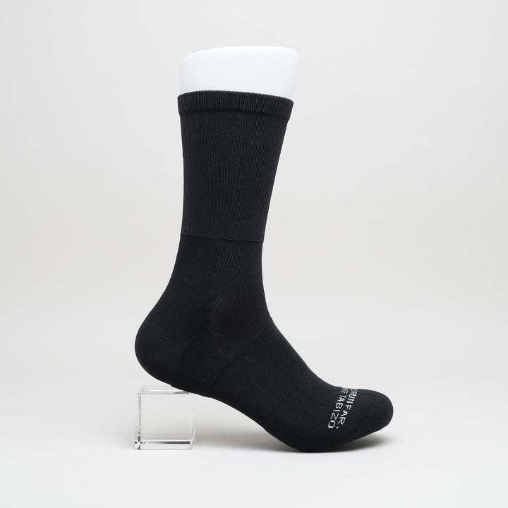 Black crew-length trail running socks with compression zones at the ankle and arch, designed for trail running and fastpacking.