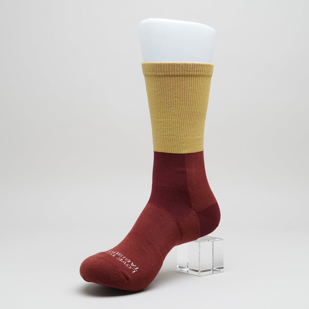 Mustard crew-length trail running socks with foot-mapped knit structure and supportive compression for trail running and fastpacking.
