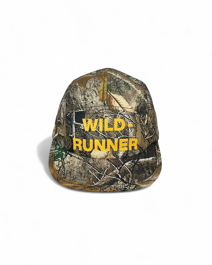 Lievre Running Wild Runner cap with camouflage print and bold “WILD-RUNNER” yellow text on front, five-panel silhouette with flat brim.